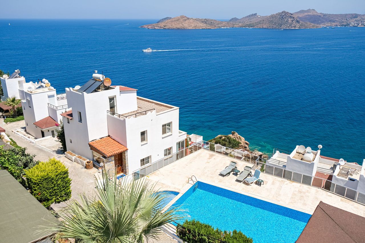 Whitewashed residences and a pool terrace above the sea at a coastal resort